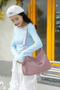 Détail d'un sac hobo en nylon rose avec bandoulière large griffée et logo métallique