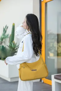 Photo de sac bandoulière en nylon jaune vif avec large sangle logotée et cordon latéral