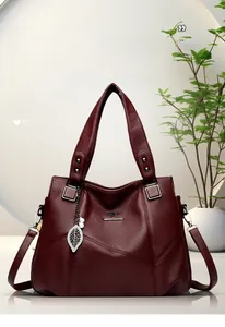 Makroansicht der weinroten Ledertasche mit silbernem Känguru-Logo und Perlenanhänger