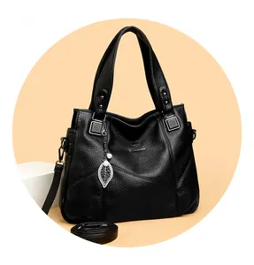 Detail der schwarzen Handtasche aus Narbenleder mit Blattanhänger und Perlenakzent