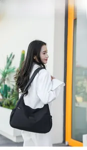 Photo en extérieur d'un sac à bandoulière en nylon noir imperméable porté par un mannequin