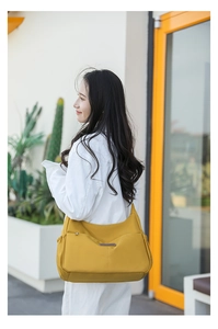 Détail du sac bandoulière en nylon jaune avec poche latérale et grand compartiment avant