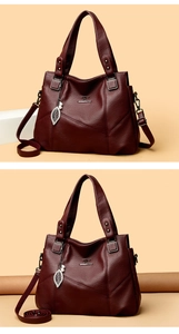 Detail der weinroten Handtasche mit Känguru-Logo, Blattanhänger und Lychee-Muster