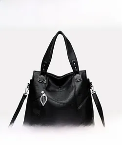 Detail der schwarzen Handtasche aus Leder mit Silberbeschlägen und Blatt-Anhänger