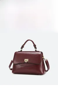Detail of burgundy leather handbag showing the gold metal clasp and high-quality stitching