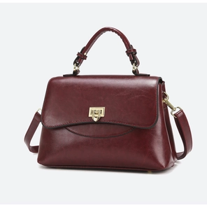 Detailed view of burgundy faux leather handbag with golden lock and top handle