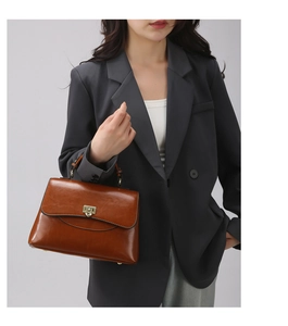 Detail of brown vintage handbag featuring a glossy finish and gold metal buckle closure