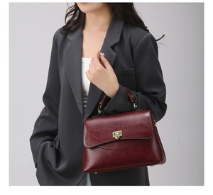 Detailed view of dark red leather handbag featuring a vintage flip cover and gold metal lock