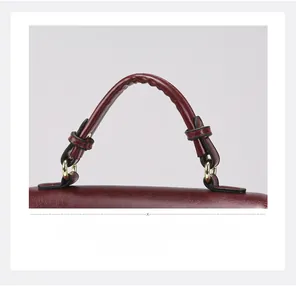 Detail of wine red faux leather handle with gold hardware and fine stitching on a handbag