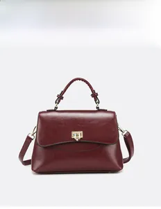 Detail of burgundy PU leather handbag with elegant gold metal twist lock and top handle