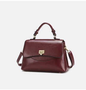 Detailed view of wine red shoulder bag featuring polished PU leather and golden clasp