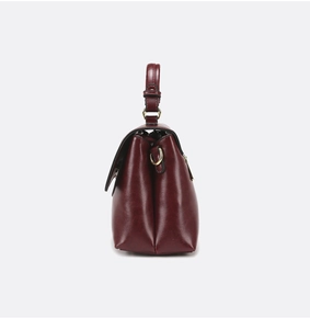 Detail view of burgundy vintage handbag showing side gussets and gold metal hardware