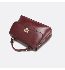 Detail of vintage burgundy oil wax leather handbag with golden metal turn-lock closure