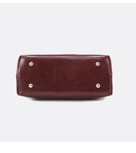 Detail view of burgundy leather bag bottom with four gold protective metal feet