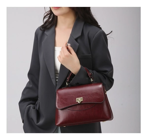 Detail of burgundy leather handbag featuring a golden square twist lock on a classic flap