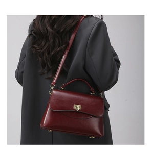 Detail of dark red vintage Boston bag with gold twist lock on a dark blazer outfit