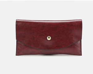Detail of burgundy textured leather envelope clutch with gold metal snap closure
