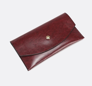 Detail of burgundy envelope wallet with vintage oil leather texture and gold metal buckle