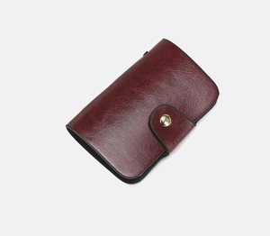 Detail of vintage burgundy card wallet with oil wax texture and gold snap closure