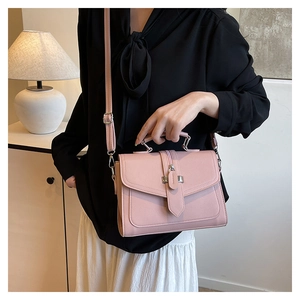 Detail of light pink PU leather handbag with lychee texture and metal clasp buckle