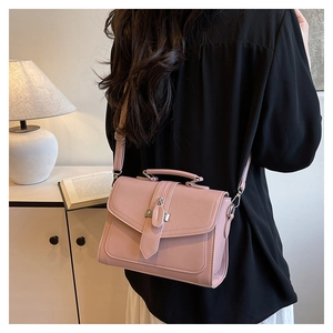 Detail of light pink pebble leather handbag with silver clasp and adjustable shoulder strap