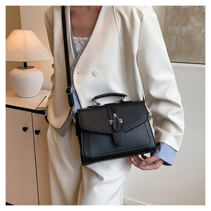 Detailed view of black litchi pattern leather handbag with flap closure and metal buckle