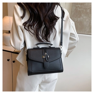 Detail showing back view of black leather crossbody bag with silver buckle on a female model