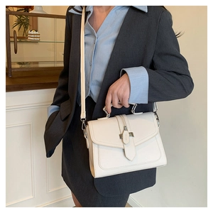 Close-up of off-white lychee grain leather handbag with silver metal buckle on strap