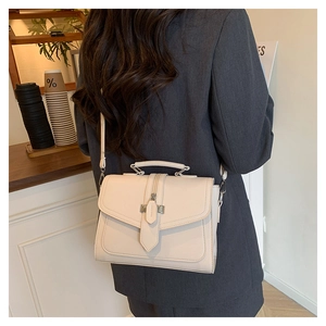 Chic cream square bag with lychee texture carried by a model in a cafe setting