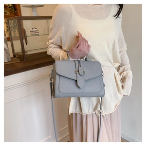 Close-up of a light blue pebble leather handbag with a metal buckle in a cozy cafe