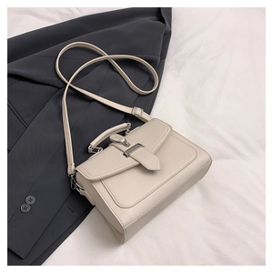 Close-up of textured off-white leather square bag with elegant silver metal buckle