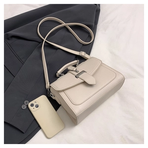 Close-up of ivory square crossbody bag featuring litchi grain leather and silver buckles