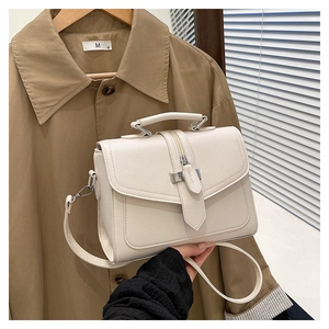 Detail of cream-white litchi grain faux leather handbag with adjustable strap