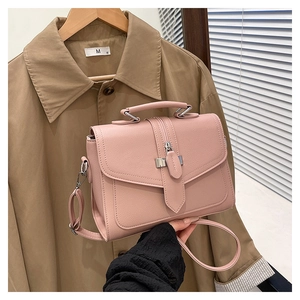 Detail of a pink square crossbody bag with lychee texture and silver hardware