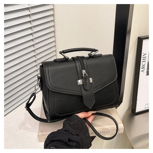 Detailed view of black litchi pattern leather square bag with silver metal lock and handle