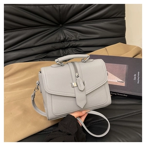 Detail view of a gray litchi texture square handbag with top handle and shoulder strap