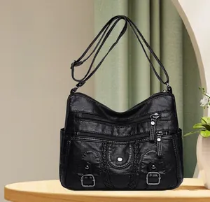 Détail du sac bandoulière en cuir noir avec plusieurs poches et boucles métalliques