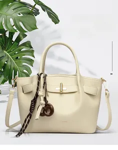 Close-up of cream leather bucket bag with gold twist lock and woven rope pendant