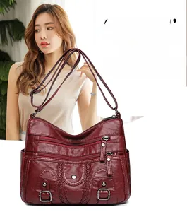 Détail d'un sac bandoulière en cuir lavé rouge foncé avec plusieurs fermetures éclair