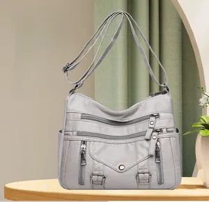 Close-up of grey multi-pocket crossbody bag with functional zippers and PU leather texture