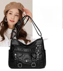 Detail showing a black leather shoulder bag with multiple zippers on female model