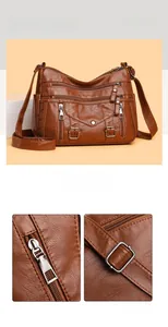 Detail view of brown multi-pocket crossbody bag with metallic zippers and leather texture