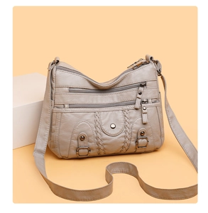 Détail d'un sac à bandoulière en cuir lavé gris clair avec plusieurs poches zippées