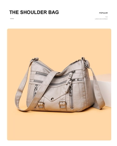 Close-up of light gray multi-pocket shoulder bag with metallic buckle and zipper details