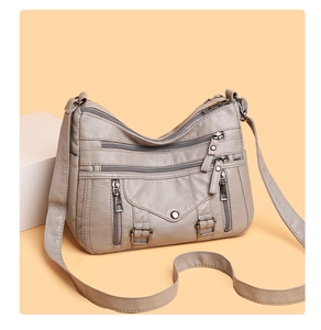Detail of light taupe crossbody bag showing soft lychee leather texture and zippers