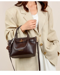 Detail of dark brown leather handbag with gold twist lock on beige blazer outfit