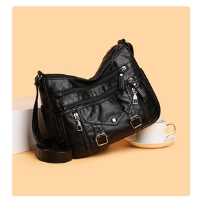 Detail of black multi-pocket crossbody bag with textured leather and silver zippers