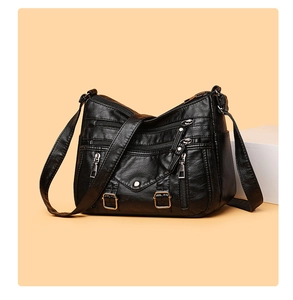 Detail view of black multi-pocket crossbody bag with silver zippers on orange background