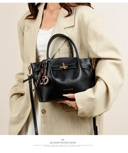 Model wearing black pebble leather tote bag with white stitching and gold turn-lock