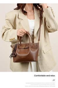 Detail of a brown leather shoulder bag featuring golden FASHION & BAGS text and M charm